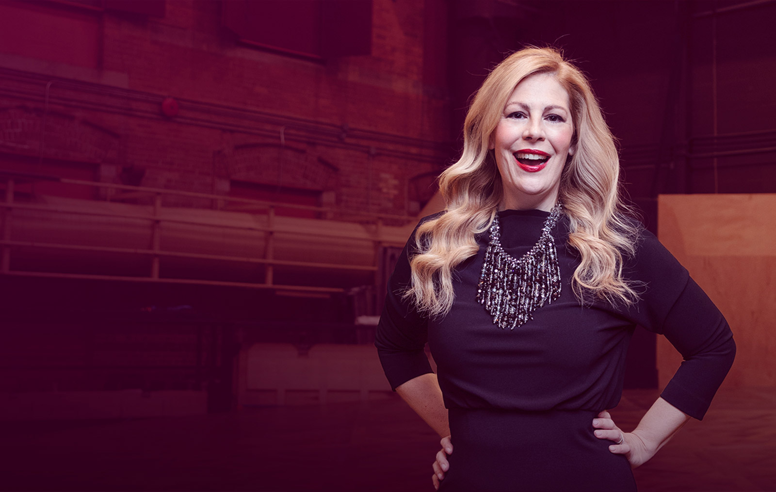 A photo of Sondra Radvanovsky wearing red lipstick and a big silver necklace. 